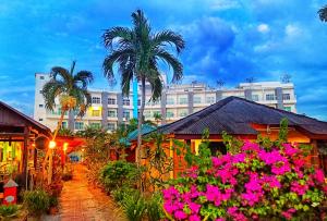 珍南海滩Langkapuri Resort Langkawi的一座棕榈树和粉红色花朵的建筑