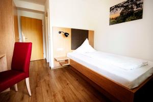施林根格拉夫旅馆的一间卧室配有一张床和一张红色椅子