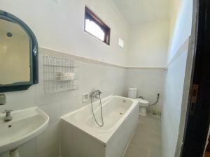 八丹拜庞多敏巴旅馆的白色的浴室设有浴缸和水槽。