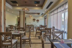 赫尔格达The Bay Hotel Hurghada Marina的餐厅设有木桌、椅子和窗户。