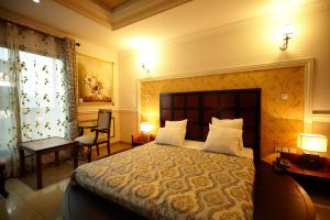 雅温得FELICIA HOTEL YAOUNDE的一间卧室配有一张大床、两盏灯和一把椅子