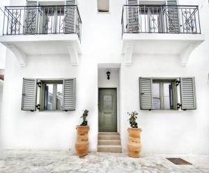 卡尔扎迈纳ANGONI SUITES的白色的建筑,设有绿门和两个阳台