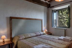 埃尔萨谷口村Agriturismo Tenuta Di Mensanello的一间卧室配有一张带两盏灯的床和一扇窗户。