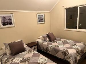 奇廉Apart Hotel Chillan - Home Cozy - Empresas - Factura - Aire acondicionado的一间卧室设有两张床和窗户。