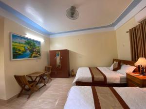峰牙Phong Nha Orient Hotel的酒店客房带两张床和一张桌子以及椅子。
