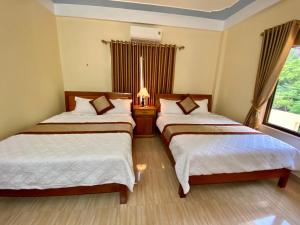 峰牙Phong Nha Orient Hotel的酒店客房设有两张床和窗户。