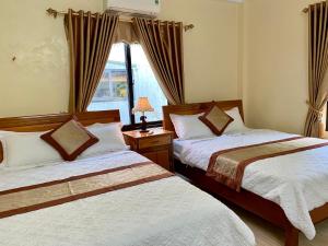 峰牙Phong Nha Orient Hotel的一间卧室设有两张床和窗户。