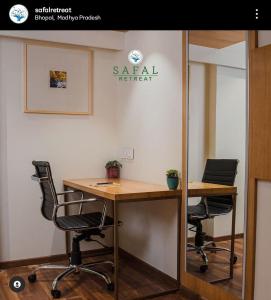 博帕尔Safal Retreat的办公室设有两把椅子、一张桌子和一面镜子