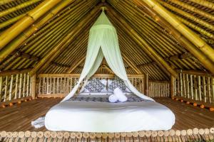 卡朗阿森Balikayanas Bamboo House - Miggiell House的茅草房内的一张大床