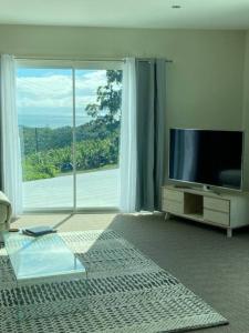 科夫斯港Ocean View Oasis, Coffs Harbour的一间带电视和大窗户的客厅