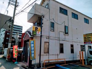 大阪Osaka Tomato Guesthouse的白色的建筑,旁边标有标志