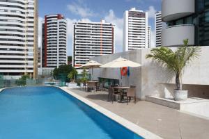 萨尔瓦多美琪尔萨尔瓦多皮图巴酒店的城市里一个带桌子和遮阳伞的游泳池