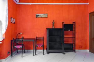 都灵Casa Metro Lingotto的橙色墙壁的房间里摆放着桌椅