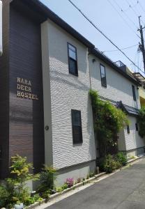 奈良Nara Deer Hostel- - 外国人向け - 日本人予約不可的白色的建筑,旁边标有标志