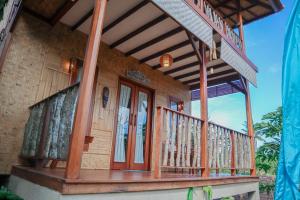 甘地达萨Jepun Didulu Cottages的带阳台的木门廊房屋