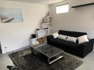 ThyleAppartement 5 personnes avec accès piscine的客厅配有黑色沙发和桌子