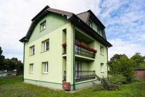BrwinówApartament Zielony Przylądek的绿色建筑,带有鲜花阳台