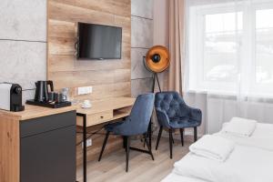 格丁尼亚Kamienica Morska Gdynia的客房设有书桌、两把椅子和电视。