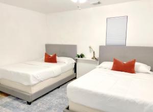 亨博尔Boho Chic的配有白色和橙色枕头的客房内的两张床