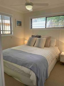 Patonga BeachPatonga Street Retreat的一间卧室设有一张大床和两个窗户。