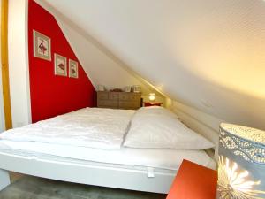 萨斯尼茨Ferienhaus Sabrina的红色墙壁的房间里一张白色的床