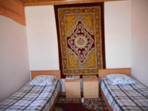 撒马尔罕OPTIMIST的一间设有两张床的客房,墙上有地毯