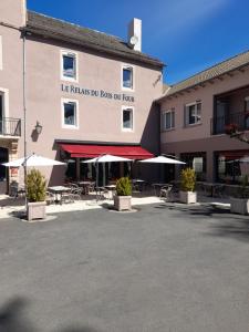 Saint-Léons瑞莱斯杜波伊斯杜弗尔酒店的停车场内带桌子和遮阳伞的建筑