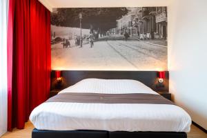 乌得勒支巴斯琛哥罗普酒店的一间卧室配有一张带红色窗帘的大床