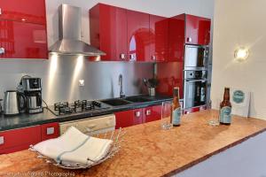 艾克斯莱班Villa Lamartine的厨房配有红色橱柜和吧台上的葡萄酒瓶