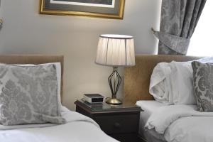 阿尼克Anglers Arms的酒店客房设有两张床和一张桌子上的台灯。