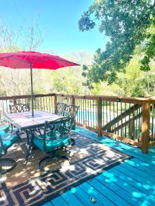 WillisGetaway Oasis w/Huge Deck + pool/spa - lake conroe的甲板上配有红色遮阳伞的野餐桌