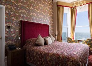 伊斯特布恩伊斯特本朗廷酒店的一间卧室配有一张带红色床头板的大床