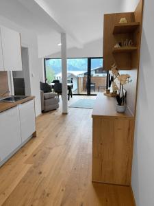 旧明斯特Traum Panorama Apartment mit Berg & Seeblick的厨房以及带白色橱柜和木地板的客厅。