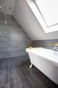 德哈恩Zalig Cosy appartement 2-4 pers.fietsen & tuin的浴室配有白色浴缸,设有天花板