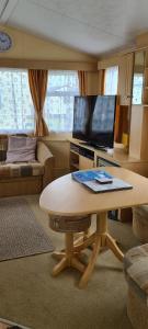 西卢港Willerby Calypso的客厅配有桌子和平面电视。