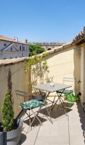 尼姆La Dolce Vita Nîmoise Terrasse 100 m des Arènes的阳台的天井配有桌椅