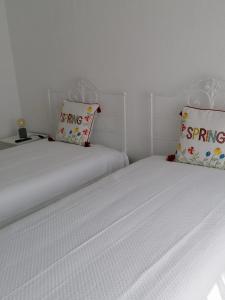 蒙塔吉尔Alojamento Justo - vila de Montargil的白色墙壁客房中的两张单人床