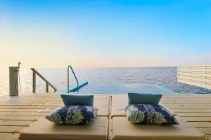 MachchafushiCentara Grand Island Resort & Spa的几个枕头坐在泳池旁的甲板上