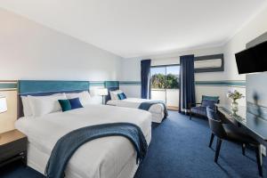 堪培拉Ramada Diplomat Canberra的酒店客房配有两张床和一张书桌