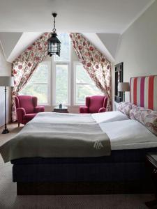 盖郎厄尔峡湾尤尼基兰格尔温泉Spa酒店的一间卧室配有一张大床和两张粉红色的椅子
