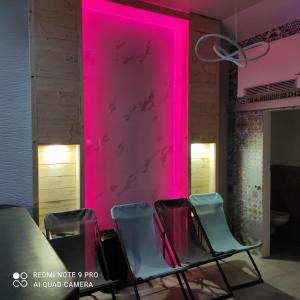 锡吉什瓦拉Casa Steluta的一组椅子,位于一个粉红色照明的房间