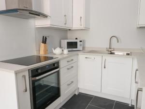 阿姆奇Tyddyn Haidd的厨房配有白色橱柜和黑烤箱。