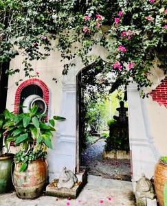 达叻府达勒艺术家广场酒店的通往花园的门道,花园内种有粉红色的花卉和植物