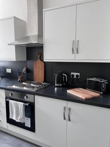 大德里菲尔德Inxpress Luxury Apartment Driffield的厨房配有白色橱柜和黑色台面