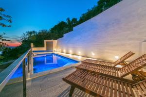 布雷拉Villa Marinkica的一座带游泳池和两个木凳的房子