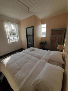 开普敦Cozy room in the Heart of Simon's Town的卧室设有一张大白色床和两个窗户