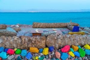 塔巴SakraTah Camp - eco friendly的海滩上设有桌子,岩石丰富多彩,海洋丰富多彩