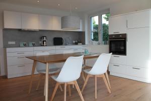 西普林根REBHAUS Ferienwohnung Weinlaube的厨房配有木桌和白色椅子