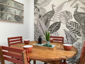 普雷兰LA MAISON DU PORT的用餐室配有木桌和孔雀壁纸