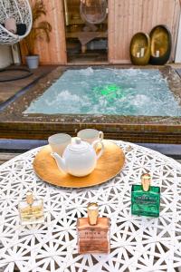 卡纳克Le Diana Hôtel & Spa NUXE的桌边的盘子上带茶壶和杯子的桌子